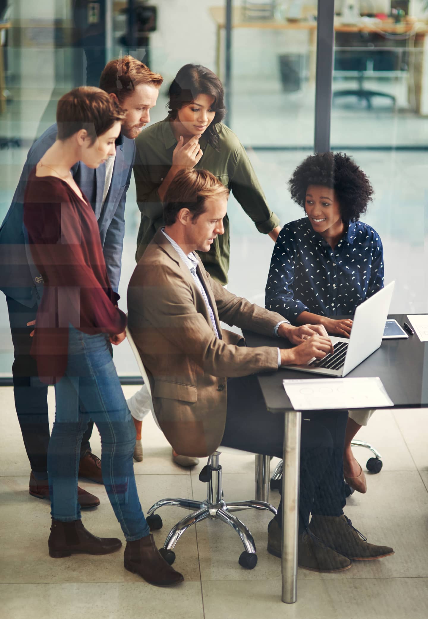 Shot of a group of colleagues using a laptop together at work